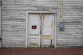 Old white painted wood building and doors with sign with no parking text on it and brick walkway Royalty Free Stock Photo