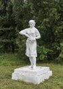 Old white plaster statue of a girl worker in a park