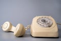 Old white rotary telephone with twisted cord on gray background. Retro landline phone with rotary dialer and remote