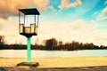 Old white and rusty metal lifeguard tower with chair on a beach. Frozen water level within witer