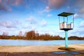 Old white and rusty metal lifeguard tower with chair on a beach. Frozen water level within witer