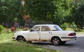 An old white Soviet car is parked in the courtyard