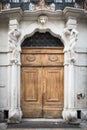 Old white stone entrance with statues and wooden portal. Royalty Free Stock Photo