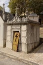 Old white stone grave tomb with loose iron cast door with cross in Alto de Sao Joao cemetery in Lisbon,