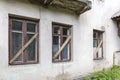 Old white plaster wall with boarded up windows Royalty Free Stock Photo