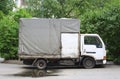 An old white truck with a closed gray body is standing near the lawn Royalty Free Stock Photo