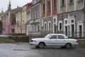 Old white Volga car parked on a cobbled side street in Kamianets-Podilskyi