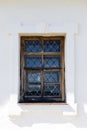 Old white wall of castle prison with a window with bars from escaping.