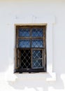 Old white wall of castle prison with a window with bars from escaping.