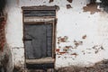 Old white wall of a house with peeling paint and an old closed door. Decrepit building. Royalty Free Stock Photo