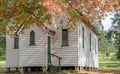 Old white weatherboard rural church surrounded by autumnal trees with multi coloured beautiful leaves Royalty Free Stock Photo