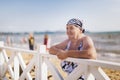 An old woman in a bathing suit and a bandana on the beach of Anapa