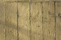 Old white yellow beige fence wall of wooden boards with cracked paint, vertical and horizontal lines and shadows. rough surface Royalty Free Stock Photo