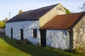 An old whitewashed stone built Irish Cottage with a small annex roofed with bangor Blue roofing tiles and rusting corrugated tin s Royalty Free Stock Photo