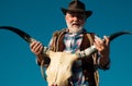 Old wild west cowboy with cow skull. Bearded western man with brown jacket and hat.