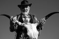 Old wild west cowboy with cow skull. Bearded western man with brown jacket and hat.