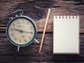 Old wind clock with notebook and pencil on wood table in vintage color scheme Royalty Free Stock Photo