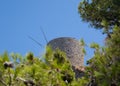 Old windmill on the background of pine trees and blue sky in Greece Royalty Free Stock Photo
