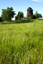 Old windmill without blades and trees next to a field