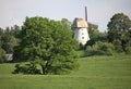 Old windmill between green trees on a hillside in Latvia on a sunny May day 2019