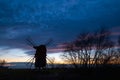 Old windmill silhouette by a cloudy sky