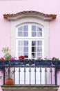 Old window with a balcony on a beautiful pink house facade