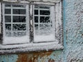 Old window with bars on a snowy frozen wall