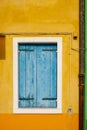 Old window with blue wooden closed blinds on the shabby yellow wall Royalty Free Stock Photo