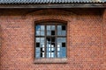 An old window with broken glass panes in a red brick wall Royalty Free Stock Photo