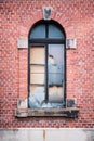 Old window. Broken glass and pieces of plywood. Red brick wall. Royalty Free Stock Photo