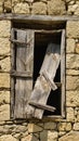 Old window with broken wooden shutter on a stone building Royalty Free Stock Photo