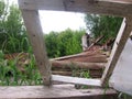 The old window frame in the destroyed wooden house was bent broken