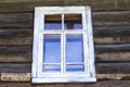 Old window with glass with a blue sky on the background of the wooden wall of the countryside log house Royalty Free Stock Photo