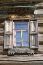 Old window with glass with a blue sky on the background of the wooden wall of the countryside log house