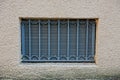 The old window with a gray iron grill on a brown concrete wall