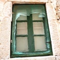 An old window with a green painted wooden frame. Dubrovnik, Croatia, old town. A torn mosquito net hangs in tatters Royalty Free Stock Photo