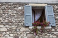 Old window with open shutters with flowers on the window sill on the stone wall. Italian Village Royalty Free Stock Photo