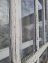 Old window with peeling white paint on the frame, focus on foreground window perspective Royalty Free Stock Photo