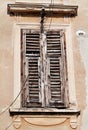 Old window with rotten and cover wooden shutters of historical building in Pula, Croatia, closeup / Building facade elements.