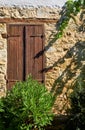 Old window with wooden closed shutters in the stone house wall. Lania village.  Limassol Royalty Free Stock Photo