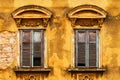 Old windows with wooden shutters on worn yellow building facade Royalty Free Stock Photo