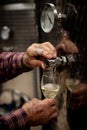 Old winemakers hands pouring a glass of wine from modern inox ta