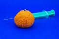 Old withered fresh orange with hypodermic needle