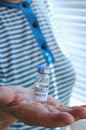 Old woman in blue t-shirt holding vaccine vial glass bottle for vaccination against COVID-19 coronavirus pandemic in her hands Royalty Free Stock Photo