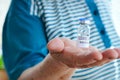 Old woman in blue t-shirt holding vaccine vial glass bottle for vaccination against COVID-19 coronavirus pandemic in her hands. Royalty Free Stock Photo