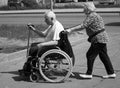 Old woman carries disabled carriage with old man