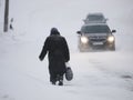 Old woman and cars at snowbound road