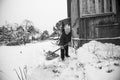 An old woman cleans the snow near her house in the village. Black and white photo. Royalty Free Stock Photo