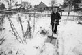 An old woman cleans the snow near her rural house in the russian village. Black and white photo. Royalty Free Stock Photo