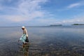 Old woman collects sea food between seaweed at low tide. A Muslim old woman wading in the Indian Ocean at low tide. Royalty Free Stock Photo